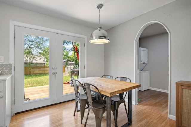 2207 Palmera Cv, Austin, TX 78744 - dining space featuring stacked washing machine and dryer, french doors, light wood-style floors, arched walkways, and baseboards
