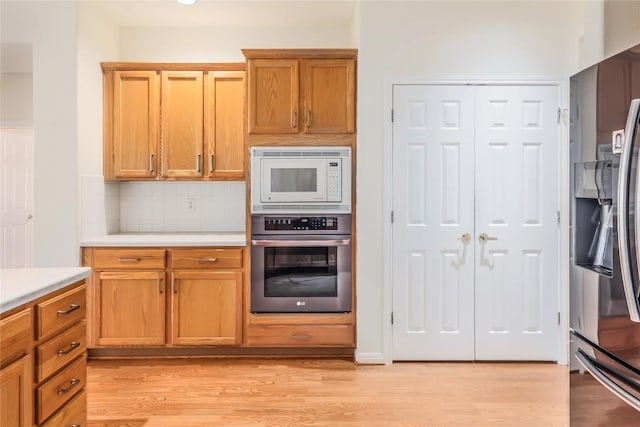 287 Red Poppy Trl, Georgetown, TX 78633 - kitchen featuring appliances with stainless steel finishes, light countertops, light wood-style floors, decorative backsplash, and brown cabinets