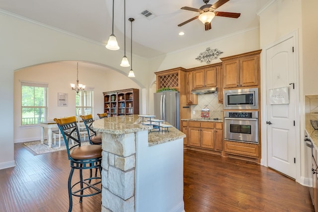 201 Thomas Ridge Rd, Burnet, TX 78611 - kitchen with stainless steel appliances, arched walkways, brown cabinetry, dark wood finished floors, and tasteful backsplash