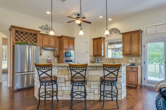 201 Thomas Ridge Rd, Burnet, TX 78611 - kitchen with appliances with stainless steel finishes, under cabinet range hood, decorative backsplash, brown cabinets, and ornamental molding
