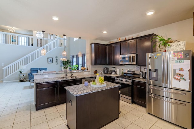 17020 Lathrop Ave, Pflugerville, TX 78660 - kitchen with stainless steel appliances, open floor plan, dark brown cabinetry, light tile patterned floors, and recessed lighting