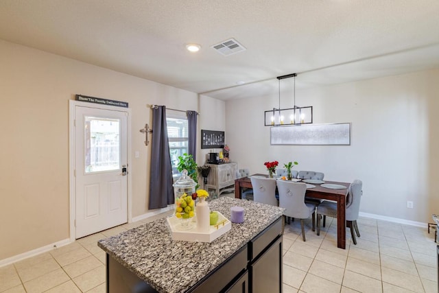 17020 Lathrop Ave, Pflugerville, TX 78660 - kitchen featuring a chandelier, light tile patterned floors, pendant lighting, a center island, and light stone counters