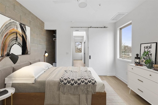 700 Denson Dr Unit 2101, Austin, TX 78752 - bedroom featuring light wood finished floors, a barn door, and baseboards