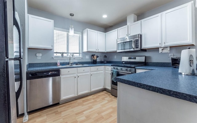 2104 New York Ave, Austin, TX 78702 - kitchen featuring appliances with stainless steel finishes, a sink, dark countertops, white cabinets, and light wood finished floors