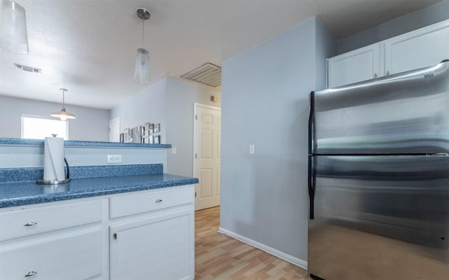 2104 New York Ave, Austin, TX 78702 - kitchen featuring freestanding refrigerator, dark countertops, light wood-type flooring, and white cabinets