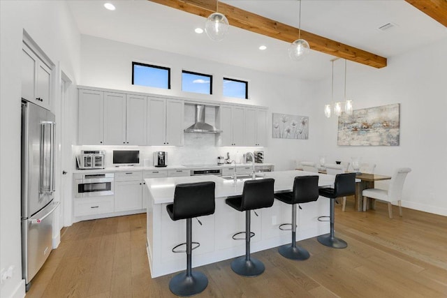 13322 Galleria Cir, Austin, TX 78738 - kitchen with stainless steel appliances, wall chimney exhaust hood, light countertops, beamed ceiling, and light wood-type flooring