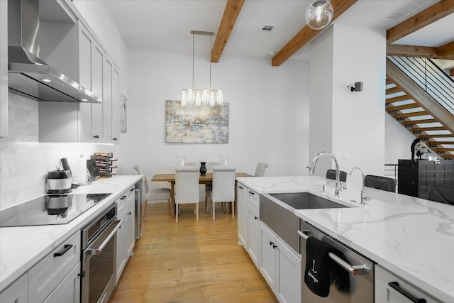 13322 Galleria Cir, Austin, TX 78738 - kitchen with wall chimney exhaust hood, stainless steel appliances, beamed ceiling, a sink, and light wood finished floors