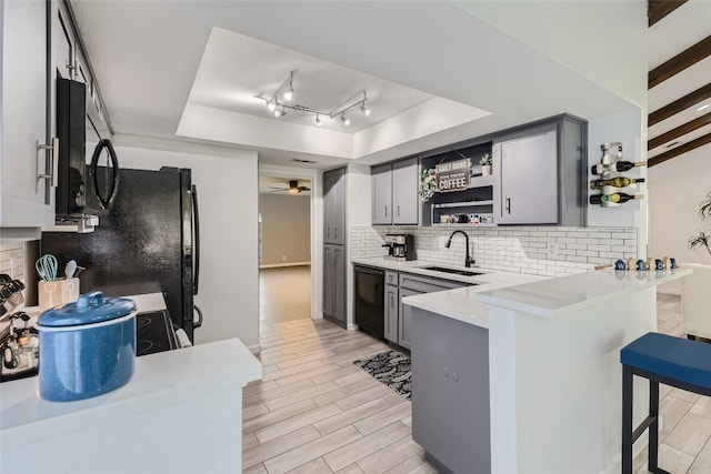 13301 Wisterwood St, Austin, TX 78729 - kitchen with a tray ceiling, a sink, black appliances, gray cabinets, and backsplash