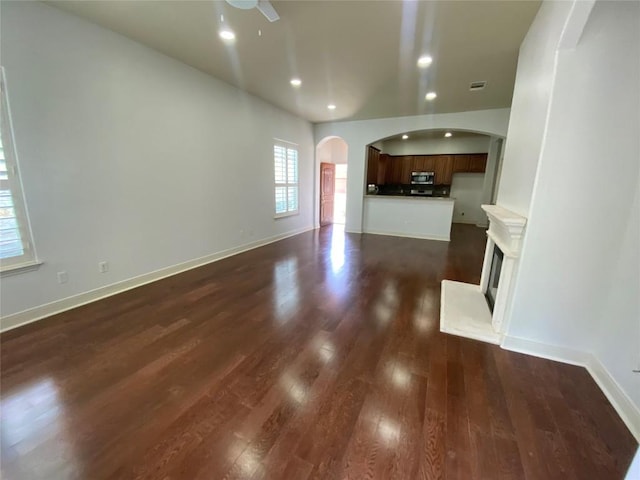 2210 Onion Creek Pkwy Unit 901, Austin, TX 78747 - unfurnished living room featuring arched walkways, dark wood-type flooring, recessed lighting, a ceiling fan, and baseboards