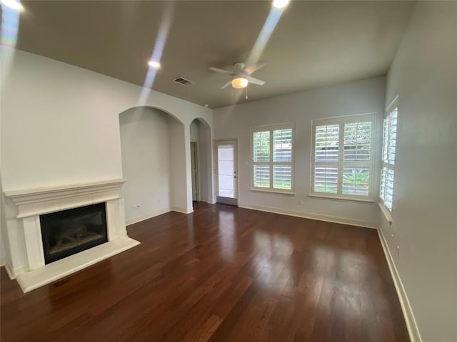 2210 Onion Creek Pkwy Unit 901, Austin, TX 78747 - unfurnished living room featuring arched walkways, a ceiling fan, wood finished floors, baseboards, and a glass covered fireplace