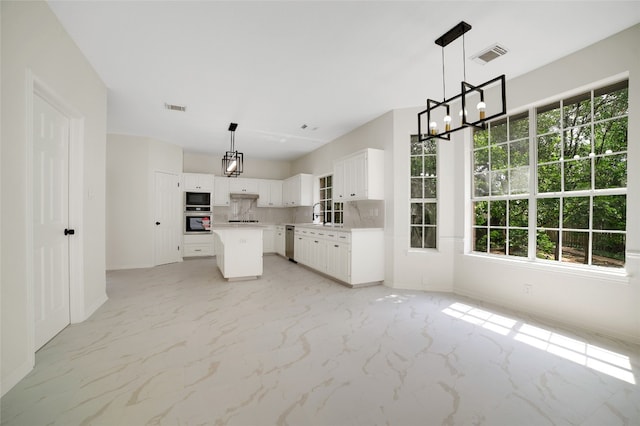 6601 Needham Ln, Austin, TX 78739 - kitchen featuring appliances with stainless steel finishes, a chandelier, a kitchen island, and light marble finish floors