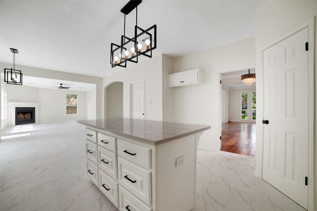 6601 Needham Ln, Austin, TX 78739 - kitchen with light marble finish flooring, a fireplace, arched walkways, open floor plan, and a ceiling fan