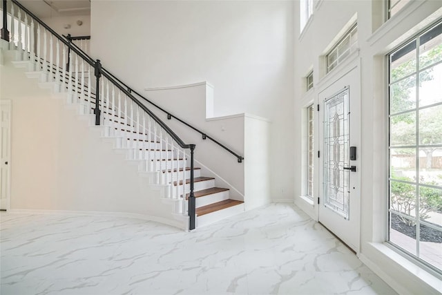 6601 Needham Ln, Austin, TX 78739 - entryway featuring marble look tile flooring, a towering ceiling, stairway, and baseboards