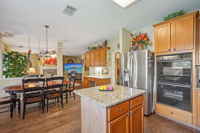 3502 Blackstone Run, San Antonio, TX 78259 - kitchen with stainless steel fridge with ice dispenser, dark wood finished floors, light stone counters, a kitchen island, and brown cabinets