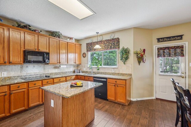 3502 Blackstone Run, San Antonio, TX 78259 - kitchen featuring black appliances, backsplash, dark wood-style floors, light stone countertops, and brown cabinets