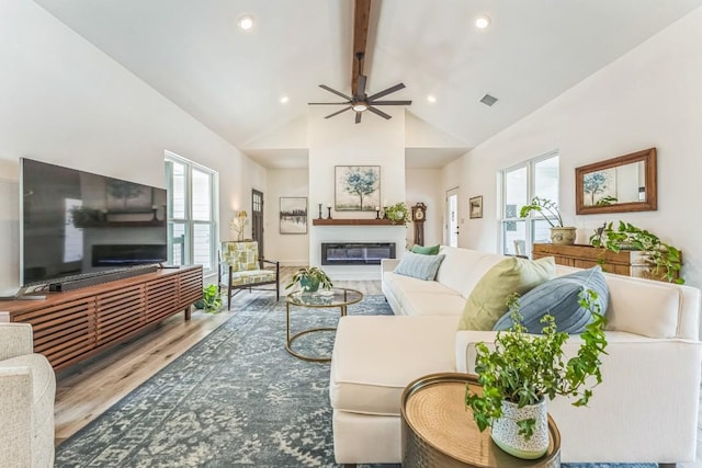 1174 Desiree St, Canyon Lake, TX 78133 - living room with a glass covered fireplace, beamed ceiling, wood finished floors, a ceiling fan, and high vaulted ceiling