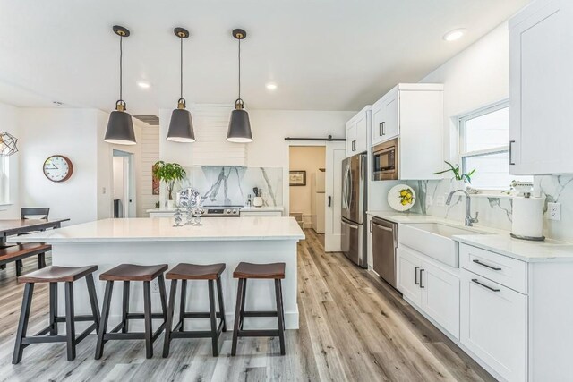 1174 Desiree St, Canyon Lake, TX 78133 - kitchen featuring appliances with stainless steel finishes, a kitchen breakfast bar, decorative backsplash, a barn door, and light countertops