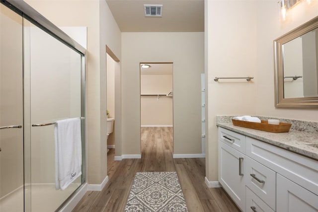 605 Silver Wing Dr, Austin, TX 78725 - full bath featuring wood finished floors, vanity, a stall shower, a walk in closet, and toilet