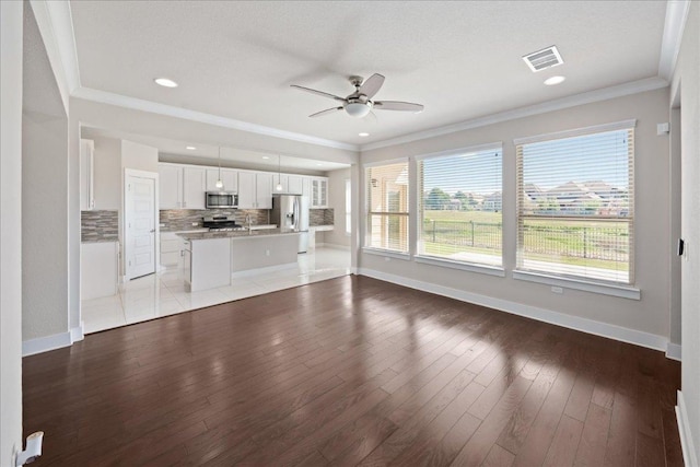 9305 Mcknight Loop Unit 4, Austin, TX 78717 - unfurnished living room featuring ceiling fan, baseboards, wood-type flooring, crown molding, and recessed lighting