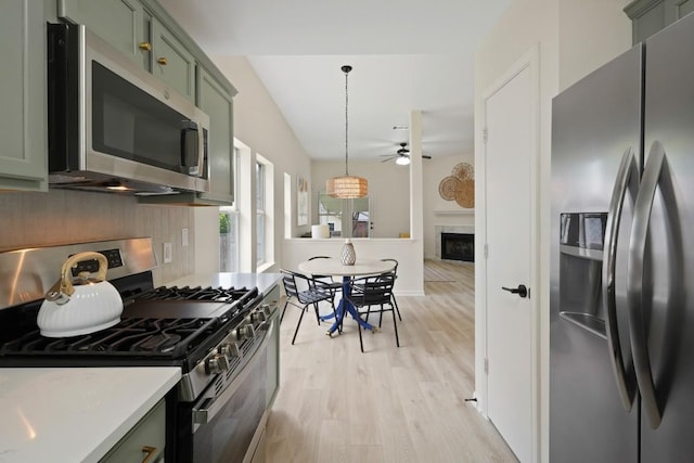 21017 Secretariat Ridge Ln, Pflugerville, TX 78660 - kitchen featuring appliances with stainless steel finishes, green cabinetry, a ceiling fan, a fireplace, and light wood-style floors