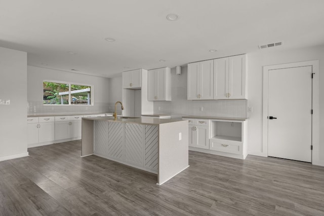 2101 Vanderbilt Ln, Austin, TX 78723 - kitchen with backsplash, an island with sink, wood finished floors, white cabinetry, and recessed lighting