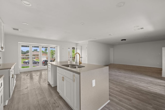 2101 Vanderbilt Ln, Austin, TX 78723 - kitchen with light wood-style flooring, white cabinetry, a kitchen island with sink, open floor plan, and recessed lighting