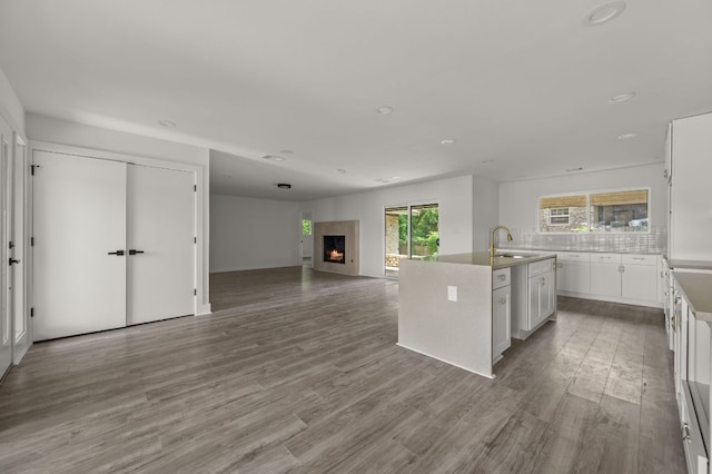2101 Vanderbilt Ln, Austin, TX 78723 - kitchen featuring white cabinets, a kitchen island with sink, wood finished floors, open floor plan, and recessed lighting