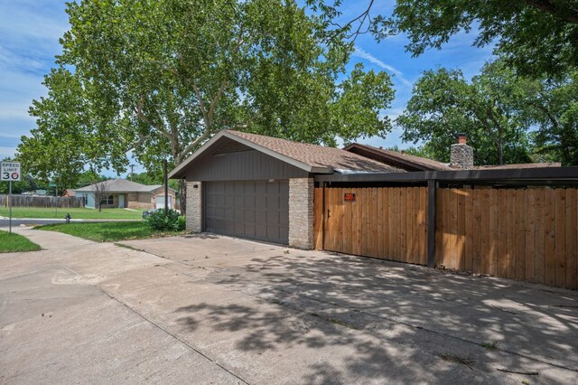 2101 Vanderbilt Ln, Austin, TX 78723 - view of property exterior with a chimney, a garage, and concrete driveway