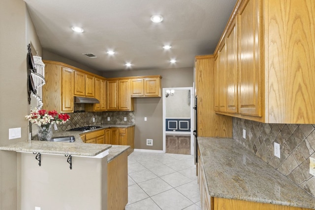 9501 Aire Libre Dr, Austin, TX 78726 - kitchen with a peninsula, light stone countertops, light tile patterned flooring, backsplash, and recessed lighting