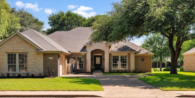 10833 Olympia Fields Loop, Austin, TX 78747 - view of front facade with stone siding, a front yard, roof with shingles, and french doors