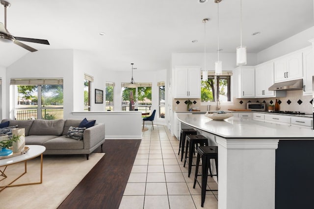 10833 Olympia Fields Loop, Austin, TX 78747 - kitchen with under cabinet range hood, ceiling fan, a kitchen bar, white cabinetry, and recessed lighting