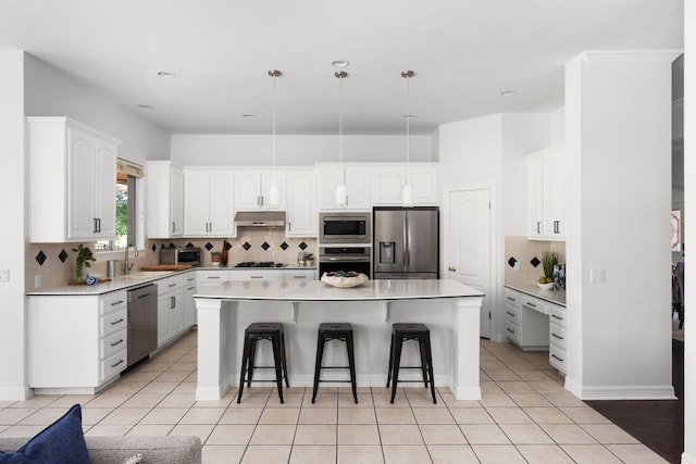 10833 Olympia Fields Loop, Austin, TX 78747 - kitchen featuring stainless steel appliances, a breakfast bar, under cabinet range hood, tasteful backsplash, and white cabinetry