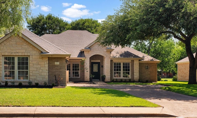 10833 Olympia Fields Loop, Austin, TX 78747 - view of front of home with stone siding, a front yard, and roof with shingles