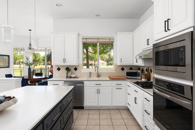 10833 Olympia Fields Loop, Austin, TX 78747 - kitchen featuring stainless steel appliances, a sink, white cabinets, light countertops, and hanging light fixtures