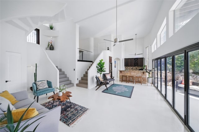 13902 Panorama Dr, Austin, TX 78732 - living room featuring a towering ceiling, stairway, ceiling fan, and finished concrete flooring