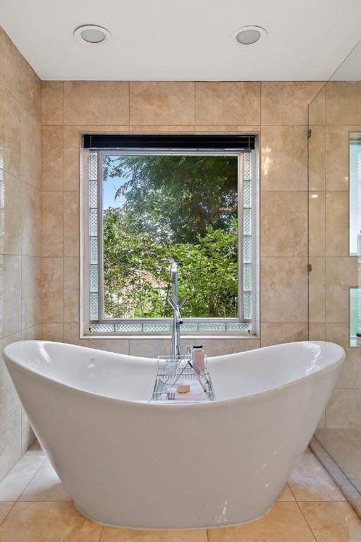13902 Panorama Dr, Austin, TX 78732 - bathroom with tile walls, tile patterned flooring, and a soaking tub