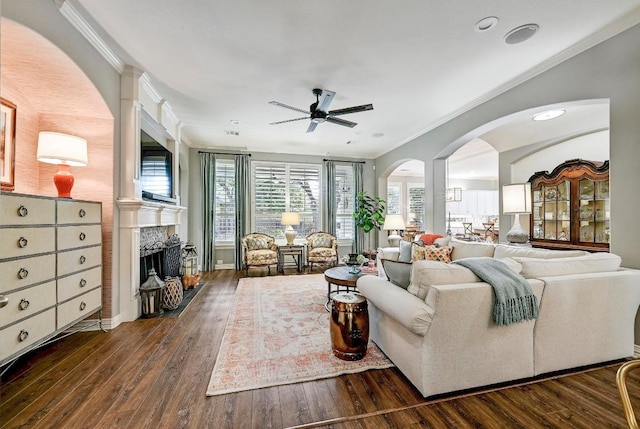 404 Riley Trl, Cedar Park, TX 78613 - living room featuring ornamental molding, a fireplace, a ceiling fan, dark wood finished floors, and arched walkways