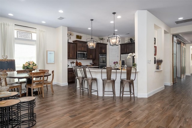 1225 Grassy Field Rd, Austin, TX 78737 - kitchen featuring appliances with stainless steel finishes, dark brown cabinetry, baseboards, a peninsula, and a breakfast bar
