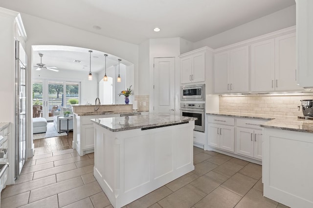 260 Unbridled, Austin, TX 78737 - kitchen featuring stainless steel appliances, a peninsula, decorative backsplash, ceiling fan, and white cabinetry