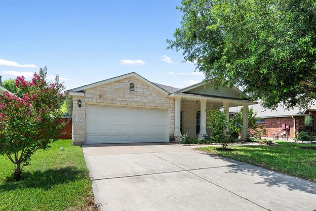 2128 Pearson Way, Round Rock, TX 78665 - view of front of property with stone siding, a front lawn, concrete driveway, a garage, and a porch