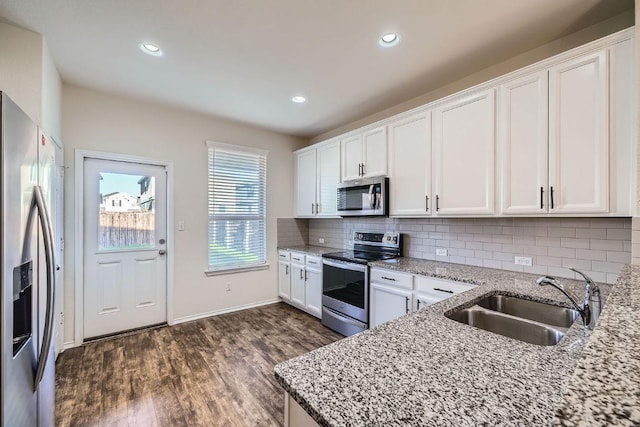 137 Green Egret Way, Leander, TX 78641 - kitchen featuring stainless steel appliances, a sink, dark wood-type flooring, white cabinetry, and tasteful backsplash