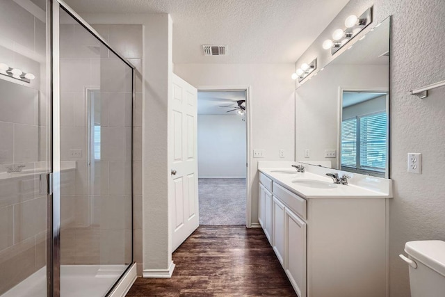 137 Green Egret Way, Leander, TX 78641 - full bath featuring a ceiling fan, wood finished floors, double vanity, a textured ceiling, and a stall shower