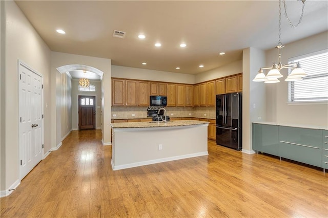 1911 Nelson Ranch Loop, Cedar Park, TX 78613 - kitchen featuring black appliances, tasteful backsplash, light wood finished floors, a sink, and arched walkways