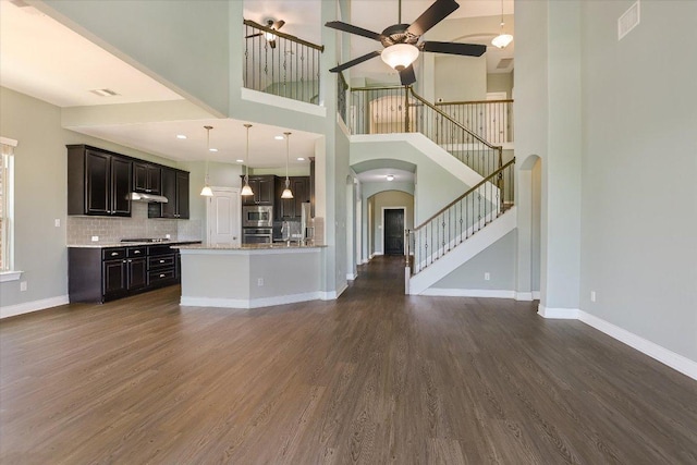 3908 Crispin Hall Ln, Pflugerville, TX 78660 - unfurnished living room featuring arched walkways, a ceiling fan, dark wood-style floors, stairway, and a towering ceiling