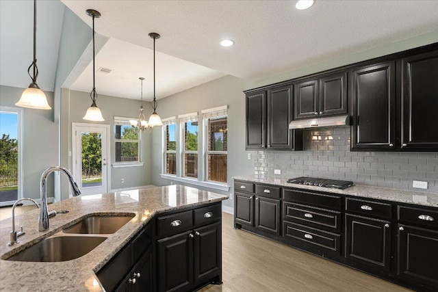 3908 Crispin Hall Ln, Pflugerville, TX 78660 - kitchen featuring dark cabinetry, a sink, stainless steel gas cooktop, light wood finished floors, and backsplash