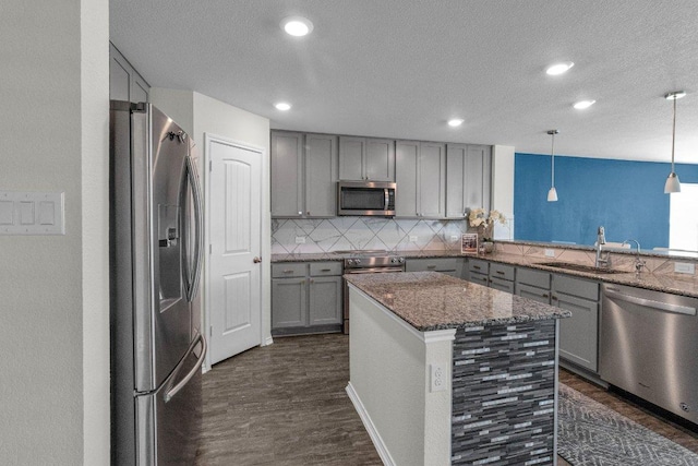 18909 James Carter Jr St, Manor, TX 78653 - kitchen featuring stainless steel appliances, gray cabinetry, dark wood-type flooring, decorative backsplash, and a textured ceiling