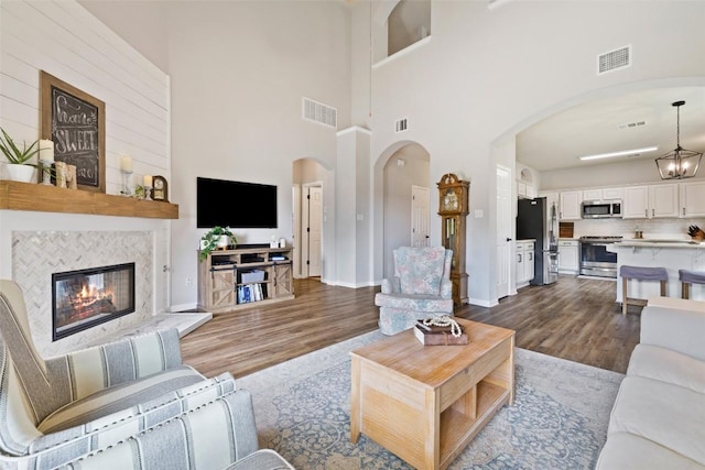 809 Bedford Ct, Georgetown, TX 78628 - living room with arched walkways, dark wood-style floors, a tile fireplace, and a high ceiling