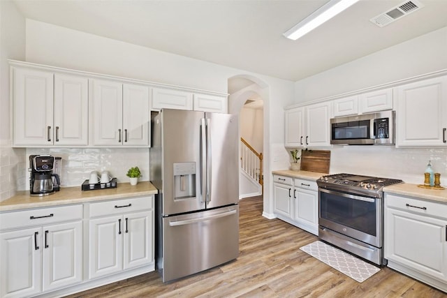 809 Bedford Ct, Georgetown, TX 78628 - kitchen with stainless steel appliances, arched walkways, backsplash, and white cabinets
