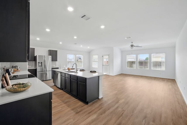 601 Sassafras St, Hutto, TX 78634 - kitchen featuring appliances with stainless steel finishes, a sink, a ceiling fan, dark cabinetry, and light wood finished floors