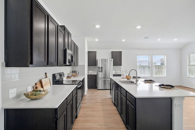 601 Sassafras St, Hutto, TX 78634 - kitchen featuring appliances with stainless steel finishes, a sink, light wood-style floors, light countertops, and backsplash